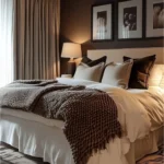 Cozy bedroom with a deep brown wall, cream bedding, warm lamps, and layered brown throws