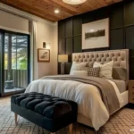 Dark charcoal bedroom with cream bedding, bedside lamps, daylight through glass doors, and a black storage bench