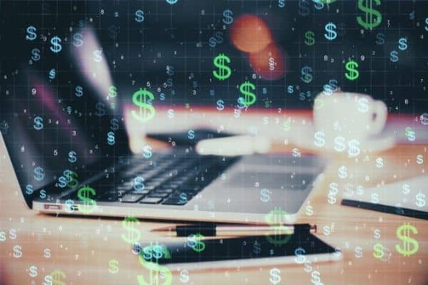 Laptop and cell phone with dollar signs floating down on photo