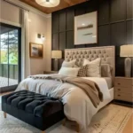 Modern bedroom with a black paneled accent wall, black upholstered bench, white bedding, and a warm wood ceiling