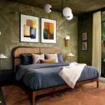 Modern couples bedroom with olive green walls, a woven cane headboard, navy bedding, and warm wood accents