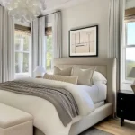 Modern neutral bedroom with a sculptural white pendant light, upholstered bed, and tall windows