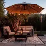 backyard patio with outdoor umbrella with string lights patio chairs outdoor table underneath at sunset