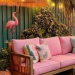 backyard with outdoor sofa with pink cushions large tiki umbrella pink flamingo string lights outdoor candles lantern