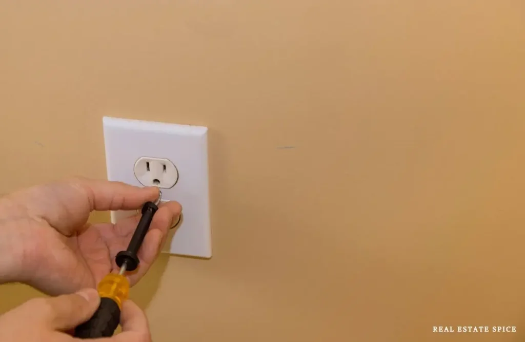hand removing an outlet cover on a wall