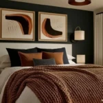 Modern bedroom with a black accent wall, cream upholstered bed, brown bedding, abstract art and wall sconces