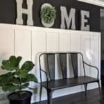 modern entryway with white board and batten wall and bench in front of wall above wall says home