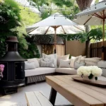 small backyard with lounge sofa picnic bench and outdoor fire pit with string bulb lights above and patio umbrellas