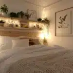 small bedroom with floating shelves above the bed framed wall art plants on shelves fairy light and wall sconce