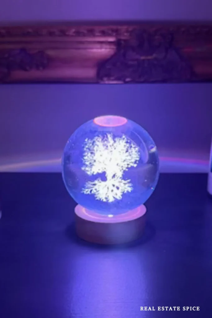 Tree of Life crystal night light glowing blue and purple on a dark wood surface.