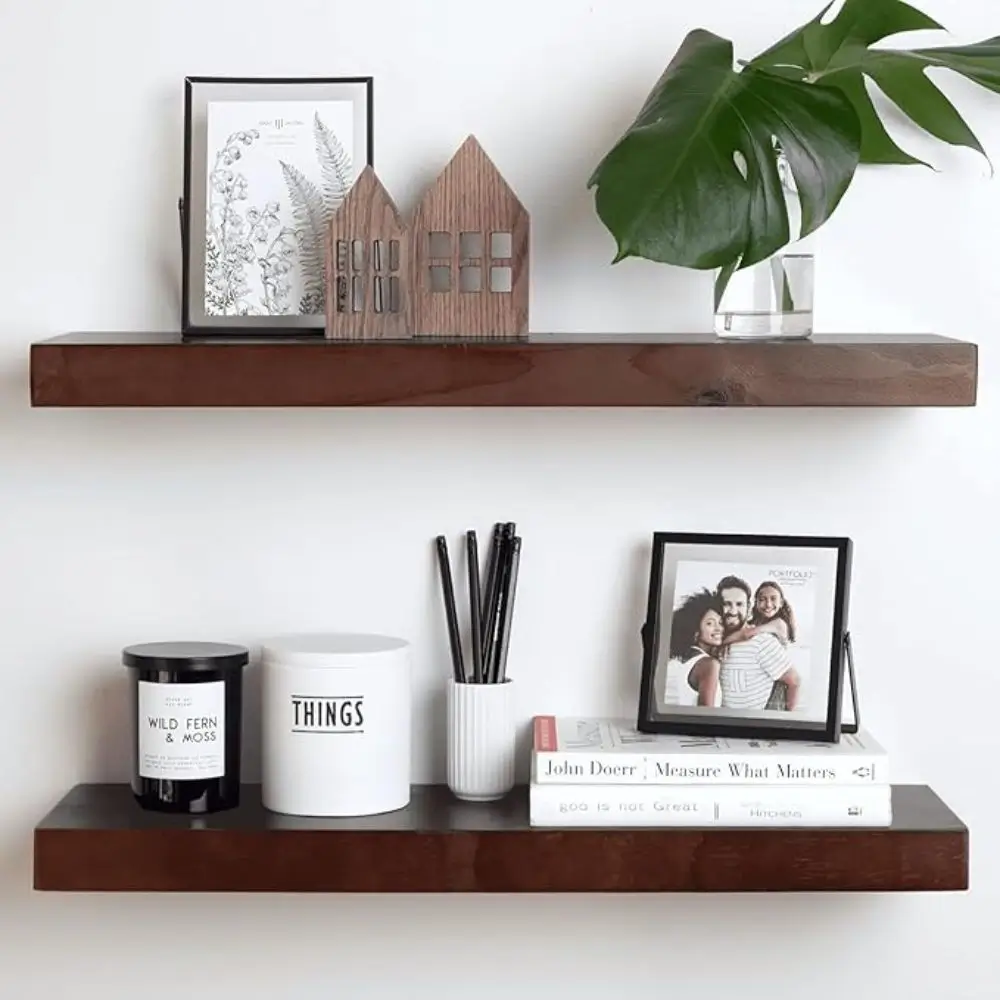 two floating wall shelves hanging on wall with home decor books candles on them