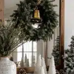 wreath hanging on mirror above a console table decorated with christmas decor